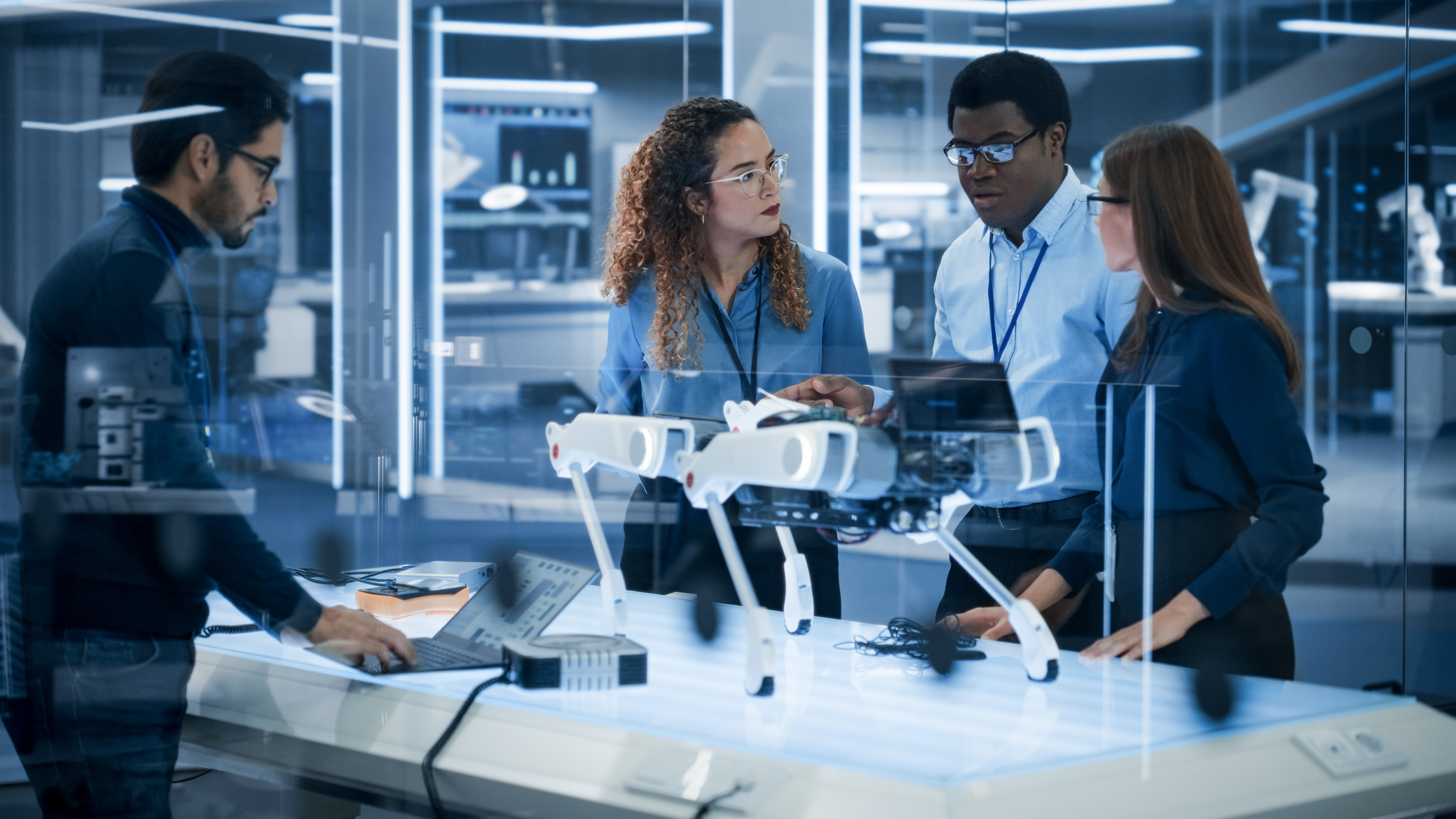 Young learners and a mentor inspecting a robotic platform in a futuristic lab